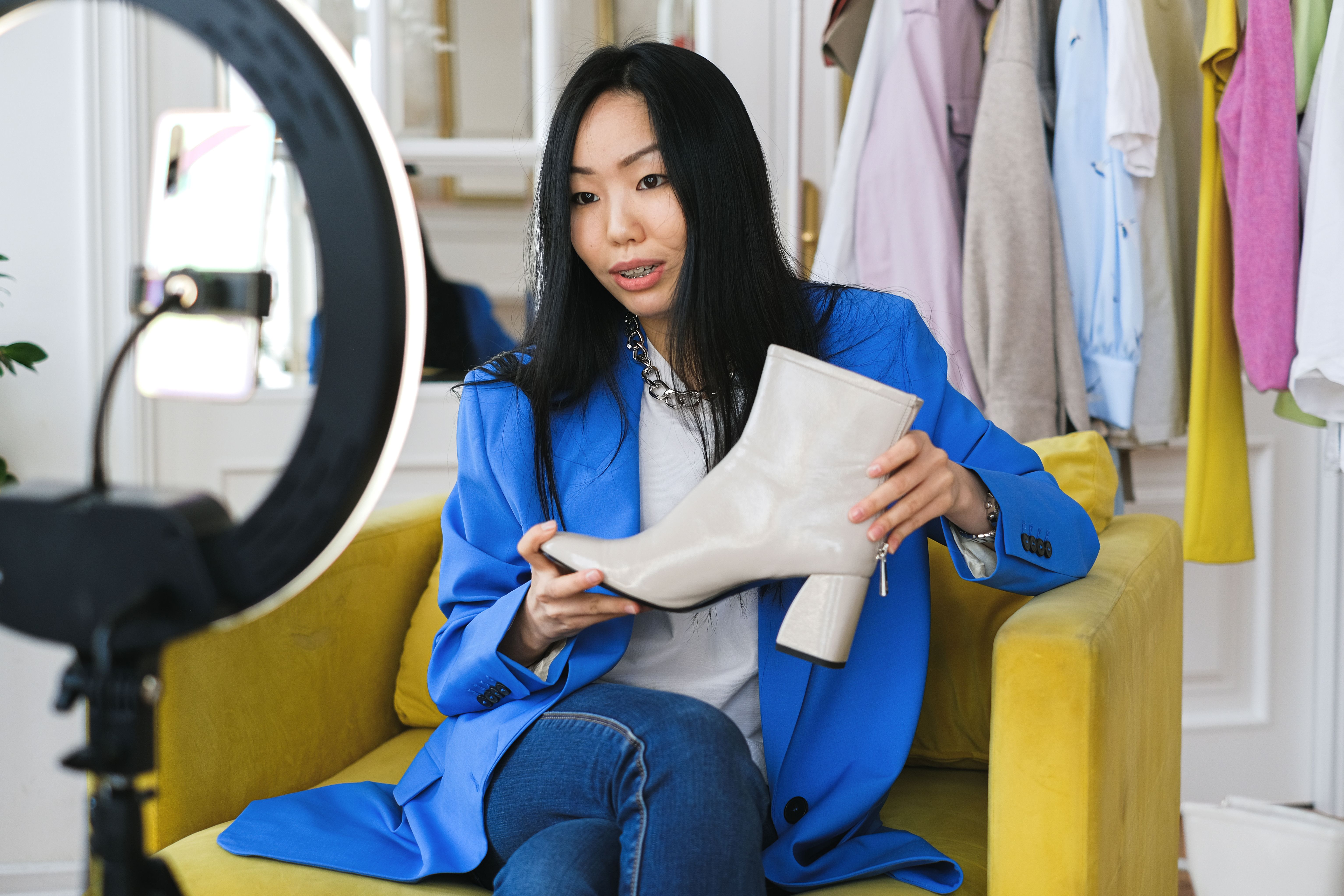 Fashion influencer reviewing shoes with a smartphone and ring light during a livestream.