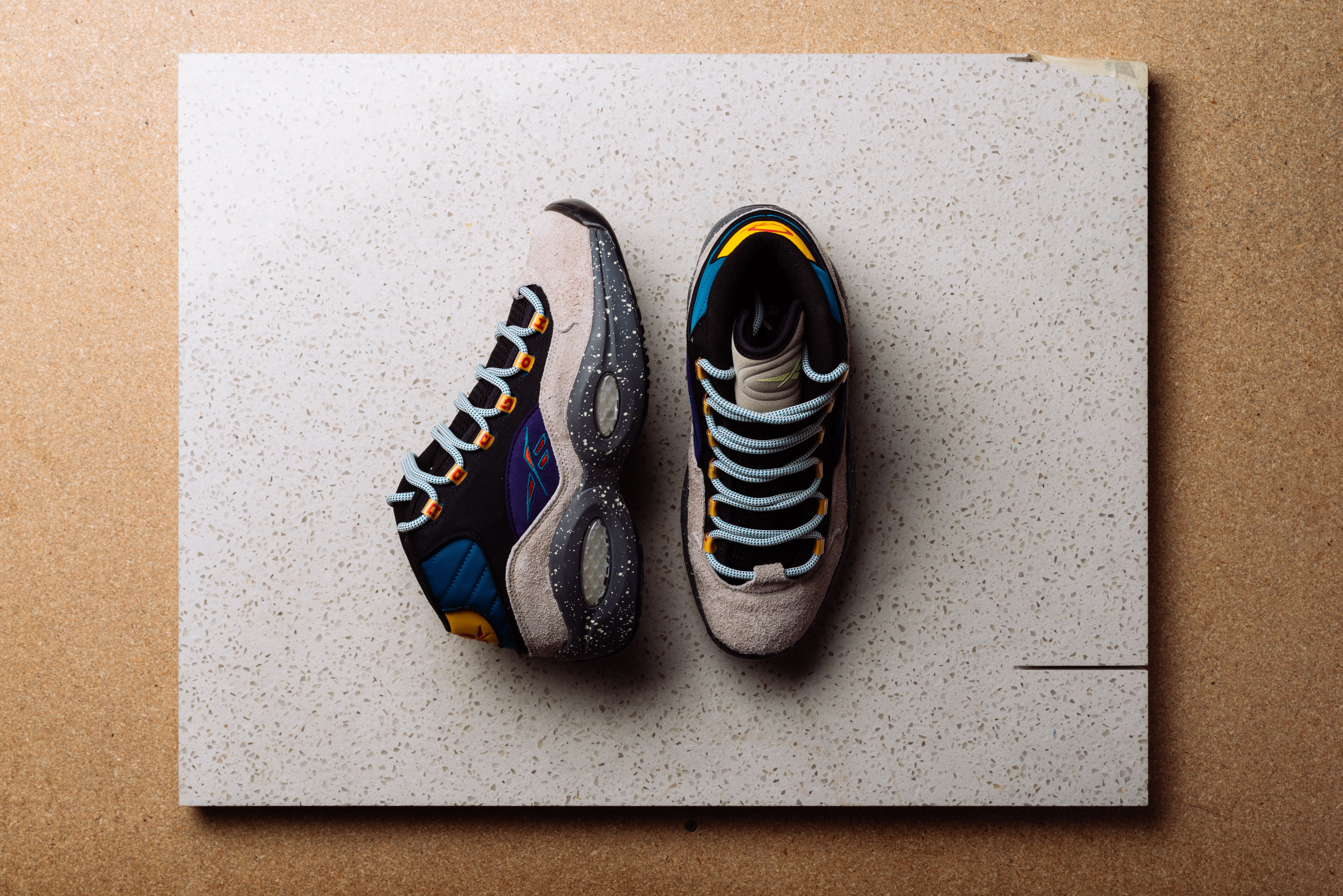 Top view of multicolor sneakers arranged on a textured background for a fashion campaign.